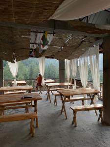 a row of wooden tables in a building with curtains at Highland spirit 2 in Kasol