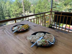 two plates of food on a wooden table on a balcony at Highland spirit 2 in Kasol +31 photos