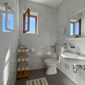 a white bathroom with a toilet and a sink at Paklenica Sport Apartments in Starigrad