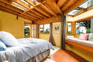 ein Schlafzimmer mit einem Bett in einem Zimmer mit Fenstern in der Unterkunft Whare Aroha: Retreat to Wellness in Pakawau