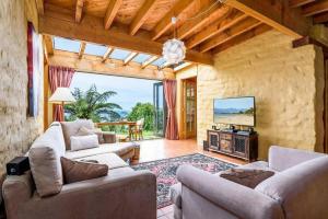 Sala de estar con 2 sofás y TV en Whare Aroha: Retreat to Wellness, en Pakawau