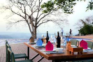 a wooden table with wine bottles and pink napkins at PIDA COFFEE FARM LODGE in Phumĭ Pu Pal