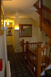 a hallway with a wooden staircase with a mirror at Gatwick Turret Guest House in Horley