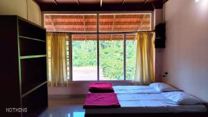 a bedroom with two beds in front of a window at Divine Gift Coorg Homestay in Suntikoppa