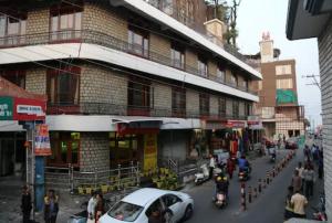 a busy city street with a building with cars and motorcycles at Goroomgo Abhinandan Mall Road Mussoorie - Luxury Room - Excellent Customer Service Awarded - Best Seller in Mussoorie