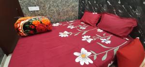 a bed with a red comforter with flowers on it at Aggarwal guest house lajpat nagar, rooms with private kitchen Android tv wifi and fridge in New Delhi