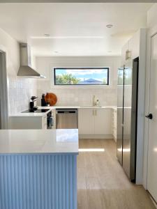 a kitchen with white counters and a large window at The Views - Omokoroa in Omokoroa