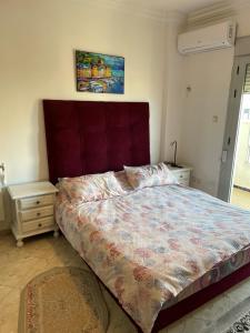 een slaapkamer met een groot bed met een rood hoofdeinde bij bel appart mosta in Mostaganem