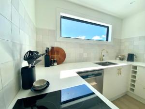 a white kitchen with a sink and a window at The Views - Omokoroa in Omokoroa