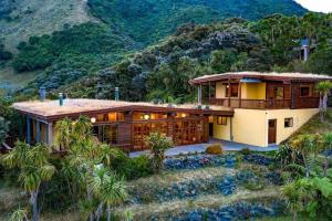 ein großes Haus mit einem Berg im Hintergrund in der Unterkunft Whare Aroha: Retreat to Wellness in Pakawau
