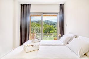 a bedroom with a white bed with a large window at Kumquart estate- Orange in Aspiotádes