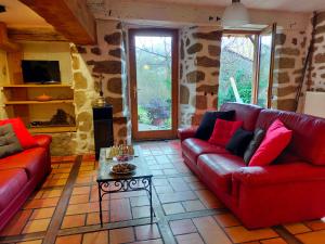 a living room with two red couches and a table at gîte Lo Jaç de Foart 10 pers. in Bosas