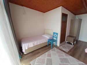 um pequeno quarto com uma cama e uma cadeira azul em ılıca anatolia pansiyon em Boyalıca