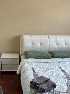 uma cama com uma cabeceira branca e almofadas verdes em Seladah Stay em Kuching