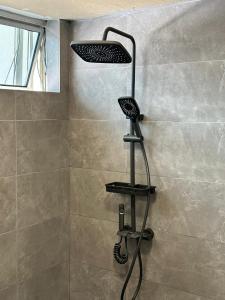 a shower with a black shower shelf in a bathroom at Seladah Stay in Kuching
