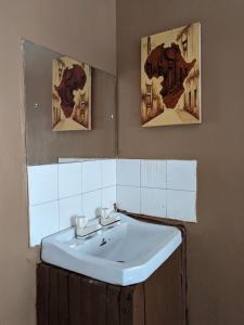 a bathroom with a sink and two pictures on the wall at Flamingo Guest House ZNZ in Stone Town