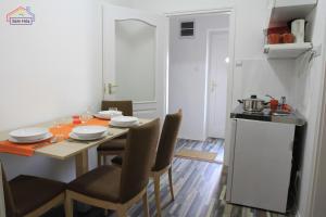 a dining room with a table and chairs and a kitchen at Szín-Ház Apartman in Gyula +20 photos