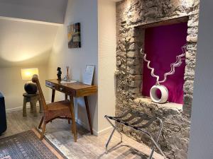 Habitación con escritorio y pared de piedra. en Les Myosotis Chambres d'hôtes - Sarreguemines, en Zetting
