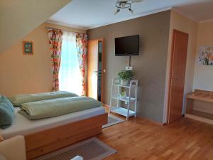 1 dormitorio con 1 cama y TV en la pared en Ferienwohnung Stoff, en Kitzeck im Sausal