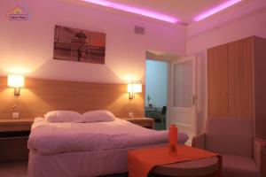 a bedroom with a bed and a chair and lights at Szín-Ház Apartman in Gyula