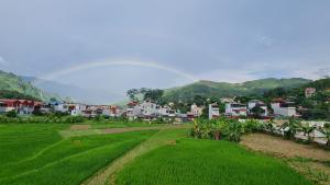 a green field with a town in the background at AKa HOMESTAY in Yên Minh