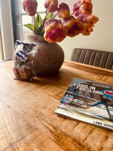 een tafel met een boek en een vaas met bloemen bij Gastenverblijf lânlibben in Lioessens