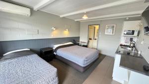 a hotel room with two beds and a kitchen at Central Court Motel in Whangarei