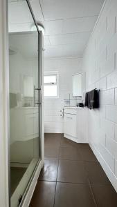 ein Bad mit einer Dusche, einem Waschbecken und einer Theke in der Unterkunft Central Court Motel in Whangarei