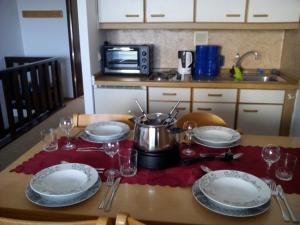 einen Tisch mit Tellern und Gläsern und einen Topf darauf. in der Unterkunft Ferienwohnung für 5 Personen ca 52 m in Sankt Englmar, Bayern Bayerischer Wald in Sankt Englmar