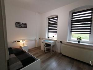 una camera da letto con un letto, una scrivania e due finestre di Ferienwohnung und Zimmervermietung Zur Alten Post a Claußnitz