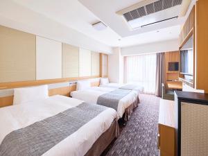 a hotel room with three beds and a flat screen tv at Vessel Hotel Campana Kyoto Gojo in Kyoto