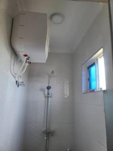 baño blanco con ducha y ventana en SULTANA APPARTMENTS, en Mwanza