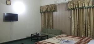 Cette chambre comprend un lit, un canapé et une télévision. dans l'établissement Decent Palace, à Lahore