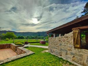 a stone house with a stone wall and a yard at Casa turística a Ardiña in Caldas de Reis