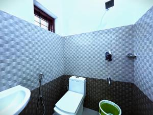 a bathroom with a white toilet and a sink at Deluxe Residency in Kalpetta