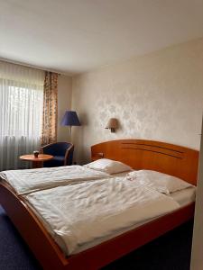 a bedroom with a large bed and a chair at Hotel Tennenloher Hof in Erlangen
