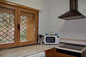 cocina con microondas blanco y ventana en 'El Mirador de Sotillo', un Oasis de Confort con Piscina y Jacuzzis, en Sotillo de la Adrada