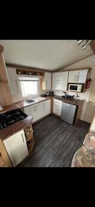 una pequeña cocina con armarios blancos y suelo de madera. en 8 berth Waterside Ingoldmells V8 Santanavan 3, en Skegness
