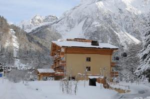 un edificio nella neve di fronte a una montagna di Hotel Garni Pegrà a Ponte di Legno