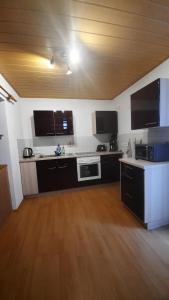 a kitchen with black and white appliances and a wooden floor at Ferienwohnung Familie Schreiter in Neudorf +16 photos
