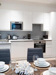 una cocina con armarios blancos y una mesa con sillas. en Apartment in Brighton en Brighton & Hove