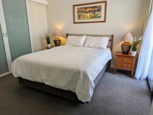 a bedroom with a large white bed with two lamps at Lovely city apartment with private courtyard, pool, free parking, gym in Perth +12 photos