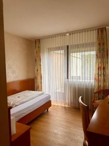 a bedroom with a bed and a large window at Hotel Tennenloher Hof in Erlangen