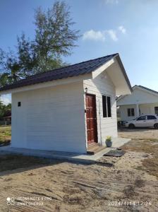 un pequeño cobertizo blanco con una puerta roja en Chalet Bonjour, en Bachok