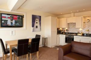 a kitchen and dining room with a table and a tv at Harbourside Apartments with Private Parking in Scarborough