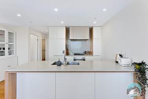 a white kitchen with white cabinets and a sink at Aircabin｜Wentworth Point｜Stylish Comfy｜2 Beds Apt in Sydney