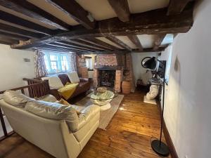 een woonkamer met een bank en een open haard bij Cosy, historic cottage, Centre Petworth in Petworth