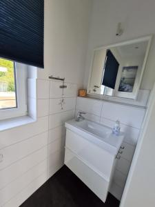 Baño blanco con lavabo y espejo en BADEBUDE 3 Ferienhaus im Hampton Style, en Oldenburg in Holstein
