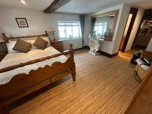1 dormitorio con cama de madera y espejo en Cosy, historic cottage, Centre Petworth, en Petworth