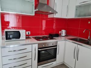 a kitchen with white cabinets and a microwave and red walls at Gjiri I Lalzit apartament in Durrës